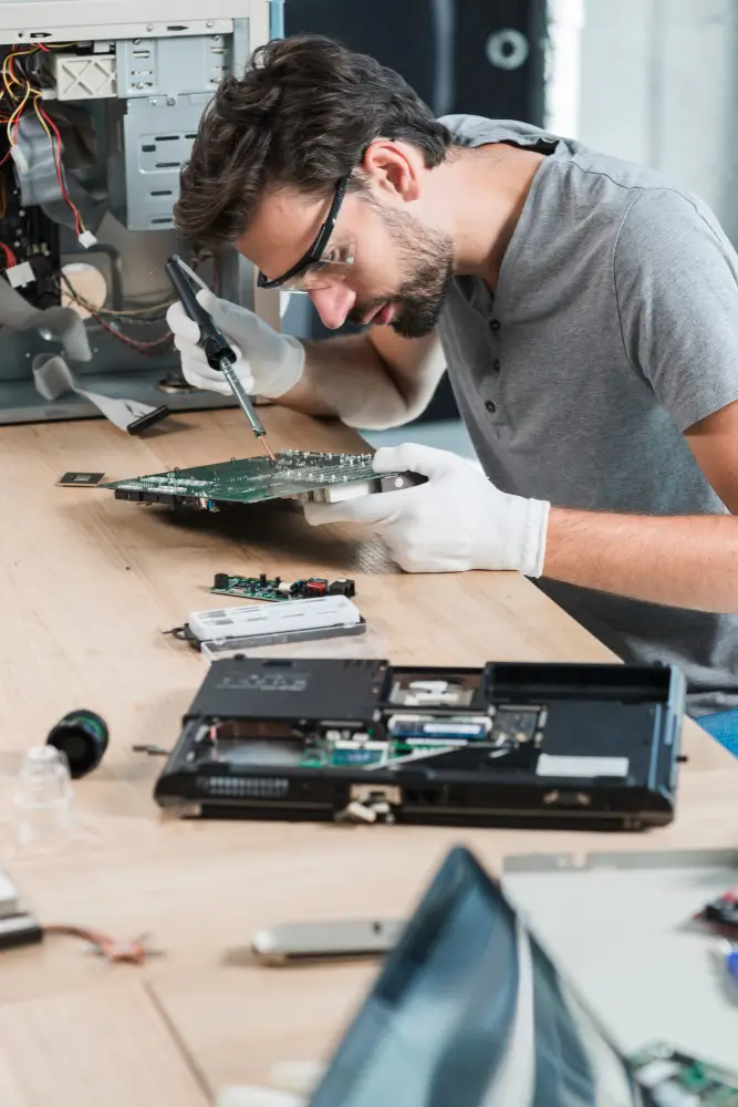 "Skilled male technician repairing computer motherboard on wooden desk - Symbolizes expertise in refurbished tech